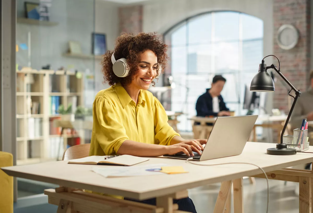 woman-smiling-on-computer-with-headphones